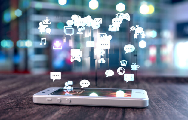 White,Smart,Phone,On,A,Wooden,Table,Emitting,Holographic,Image Small Business Tips To Succeed On Facebook: Know Your Audience, Commit Resources, And Be Genuine