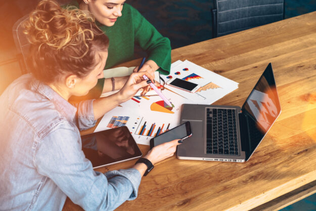 Two,Young,Business,Women,Sitting,At,Table,In,Front,Of How to Promote Your Local Business on Instagram