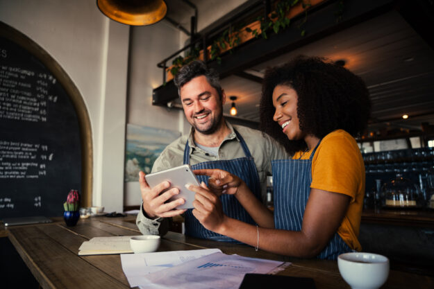 Manager,And,Waitress,Laughing,At,Designs,On,Digital,Tablet,Standing Seven Small Business Growth Strategies That Work In 2022